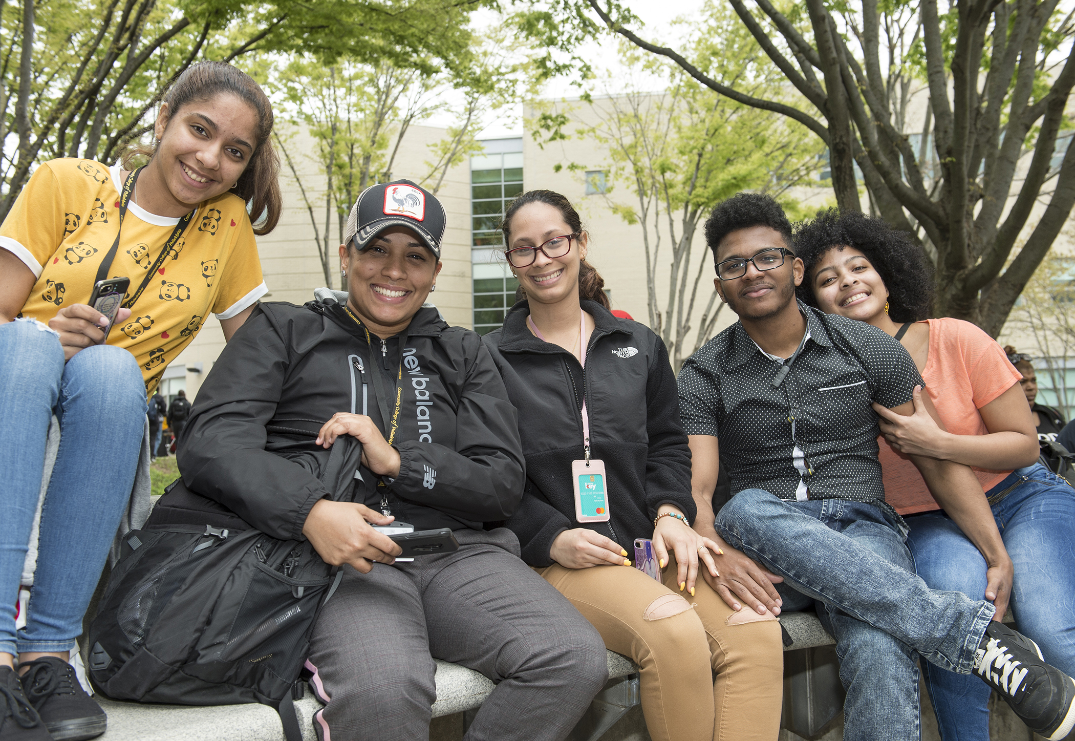 Students sitting on a ledge on campus smiling at the camera