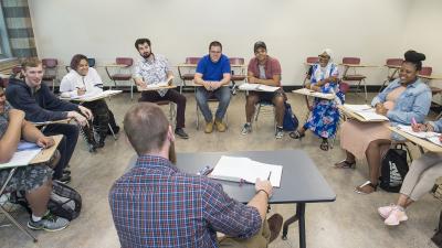 Circle of students at desks writing together during class