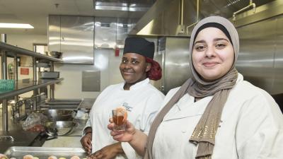 Two culinary arts students smiling with their shrimp cocktail dishes