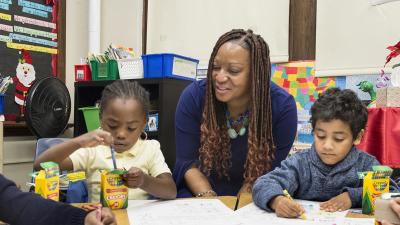 A grade school teacher watches their students color.