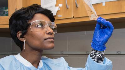 Student wearing protective gear looking at a lab sample