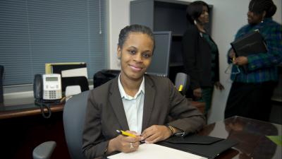 A student smiles at the camera with an open notebook.