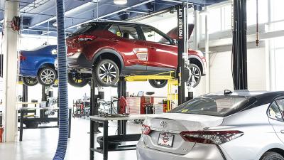 Large modern automotive garage with three cars and various tools.
