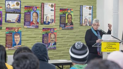 Instructor speaks to students with posters of prominent Black leaders on the wall.