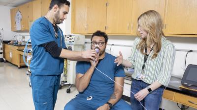 Instructor explains equipment as one student plays patient and one student plays therapist.
