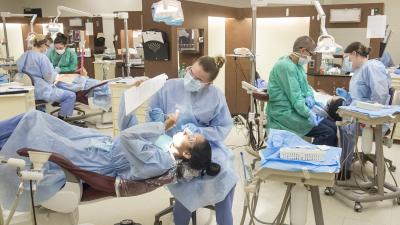 Dental hygiene students working on one another in a dental clinic.