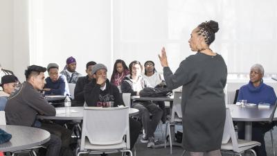 Speaking talks to students who are listening intently.