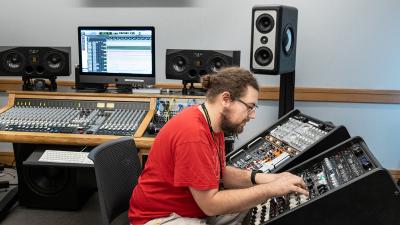 Student Works at sounding board surrounded by recording equipment.
