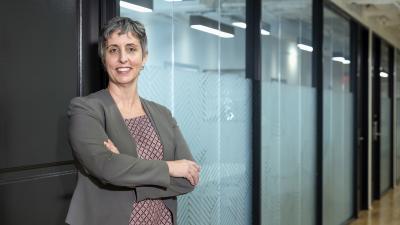 Woman in business attire stands confidently in an office hallway.