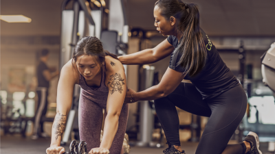 Personal trainer helping client with exercise