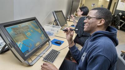 A student sits working on an architectural virtual reality interface in the design lab