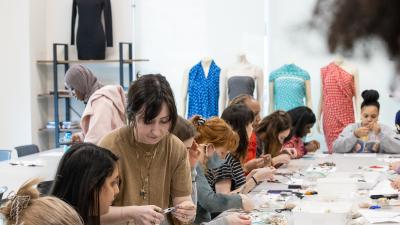 Students making jewelry in a classroom.