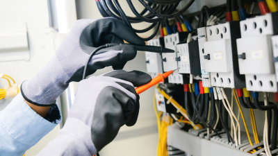 two hands with electrical gloves on testing electrical sockets