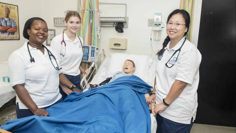 Nursing student standing over a mannequin "patient" 