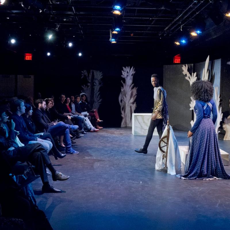 Students acting on a stage under a spotlight