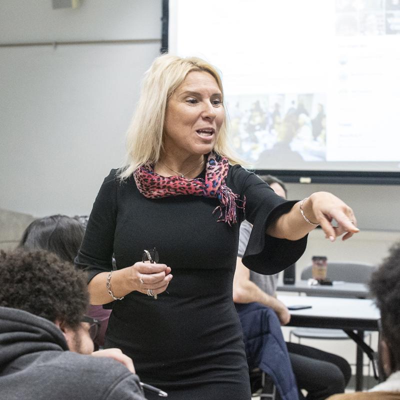 A teacher in a classroom points and speaks to a student.