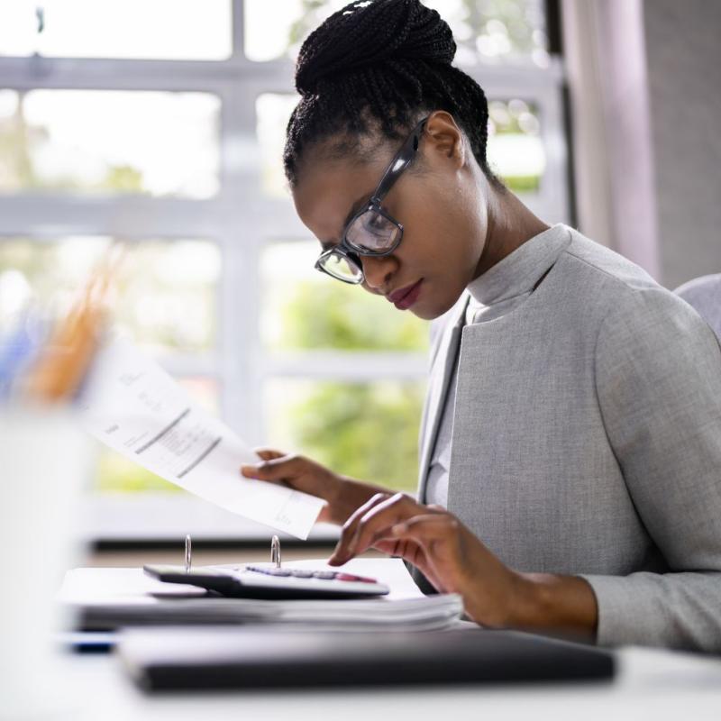 Woman at a desk calculates.