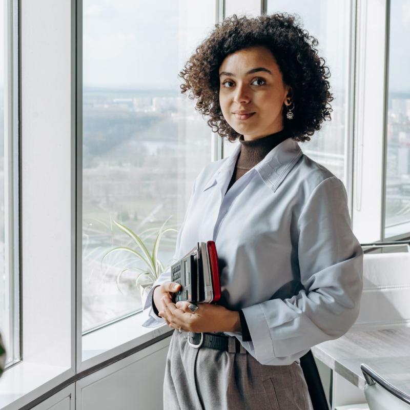 A young financial manager smiles in her office while holding financial reports