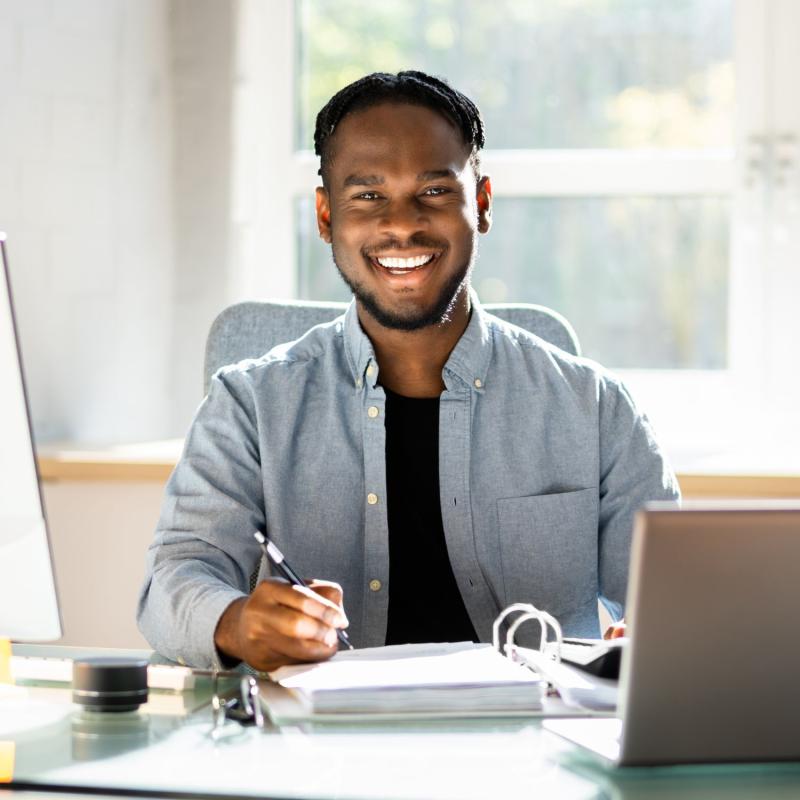 Smiling office manager seated at desk in his sunny office