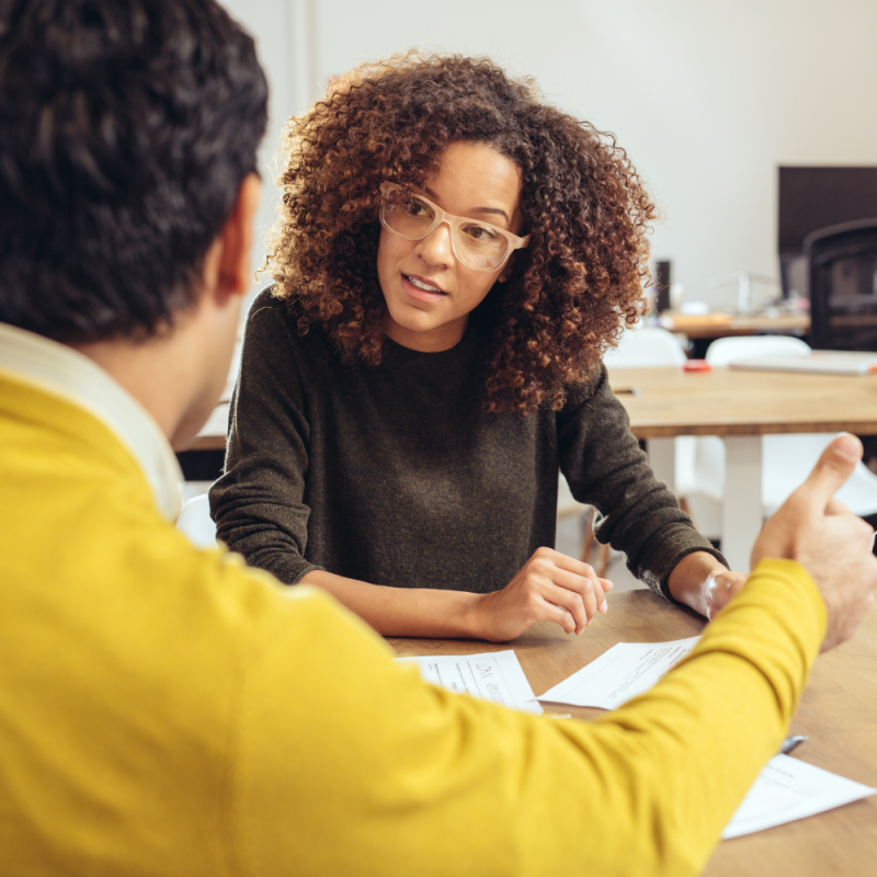 A young accountant listens to a client as they review tax information