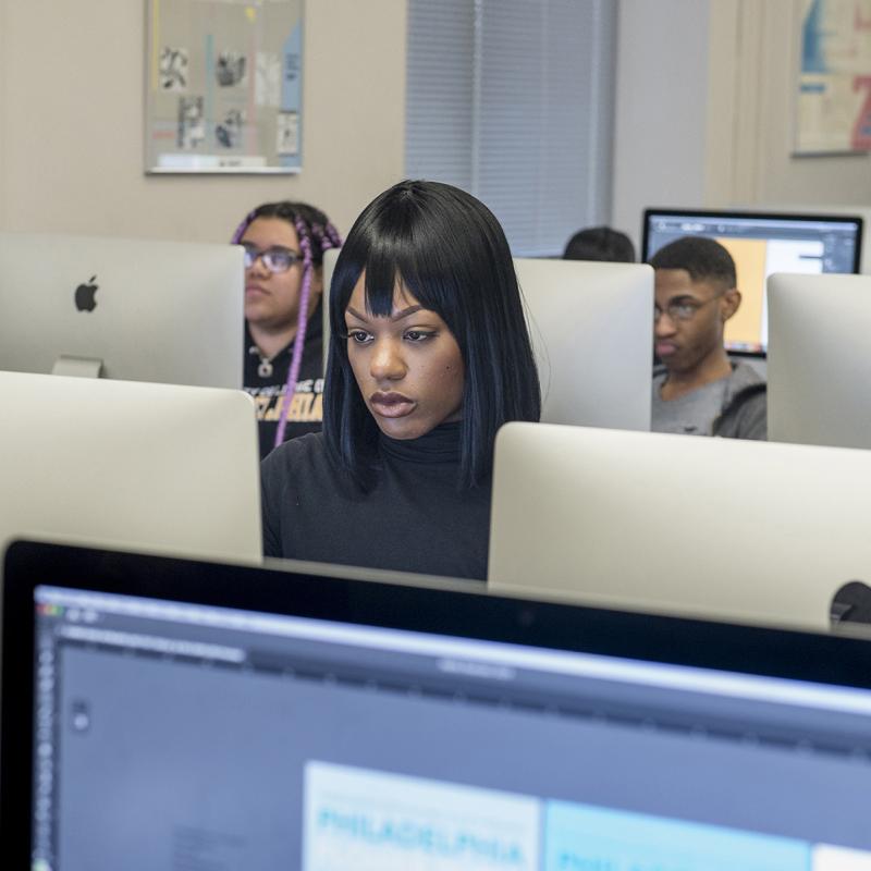 Woman in classroom works at a computer.