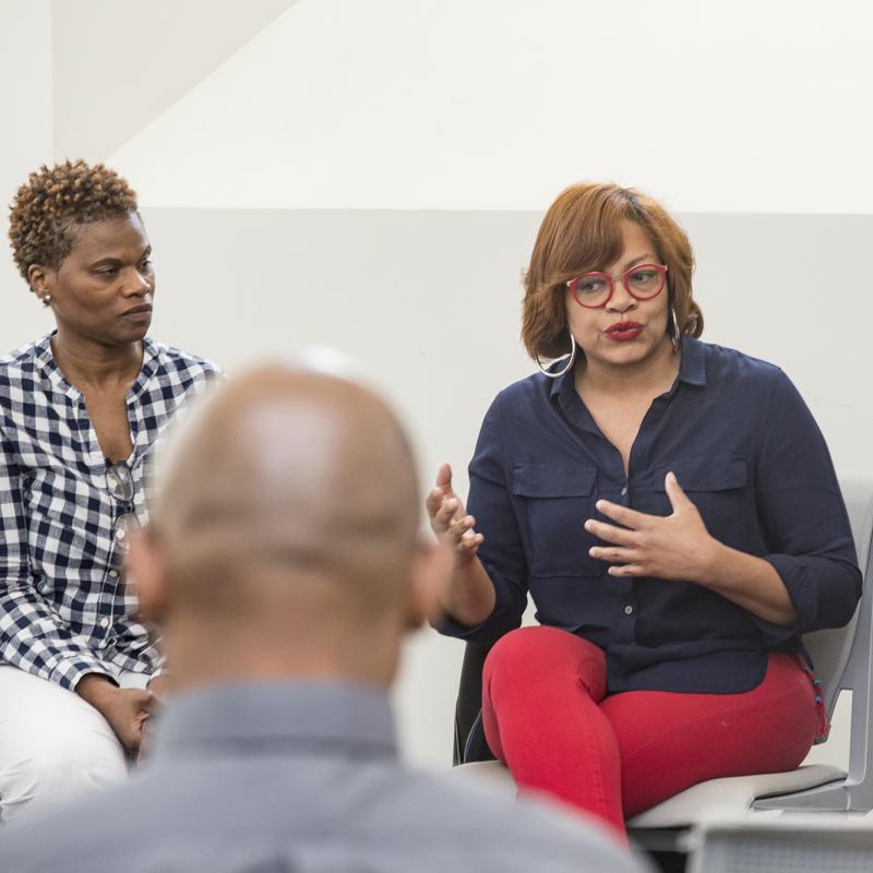 Woman speaks to a group sitting in a circle.