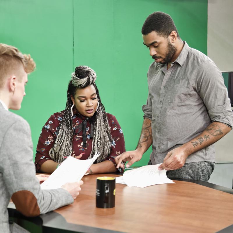 Producer and broadcasters discuss the script.