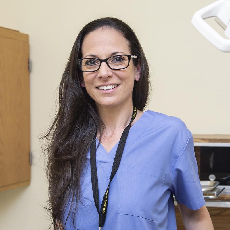 Woman in scrubs smiles for the camera.