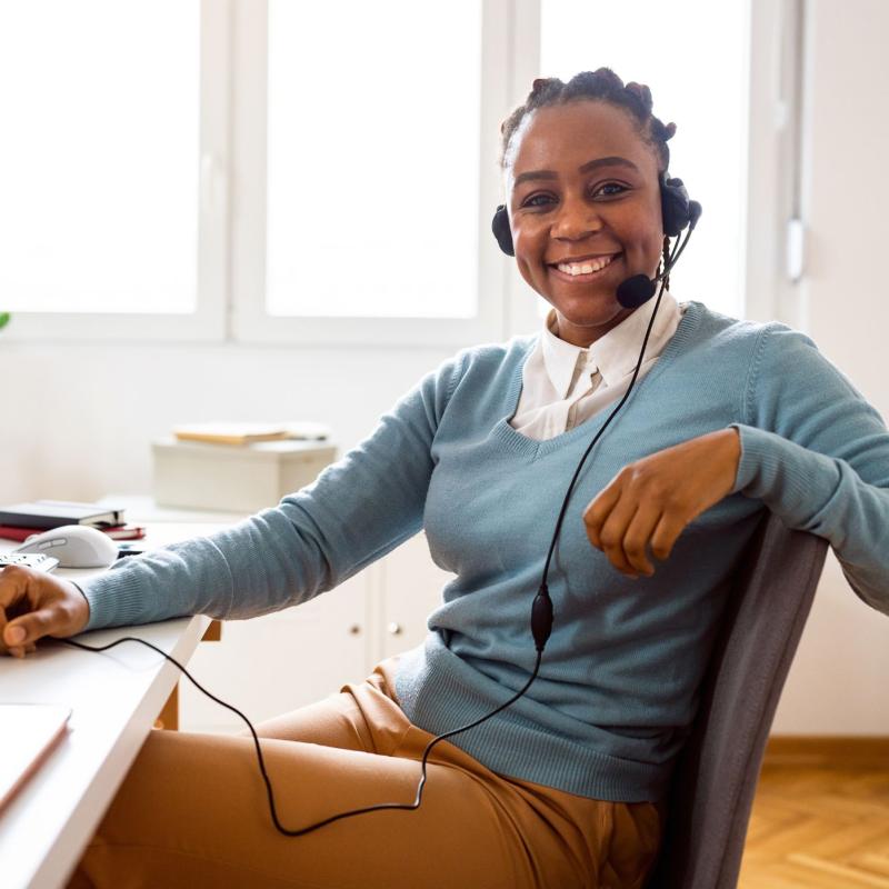 Person smiling while working at a desk and on the phone