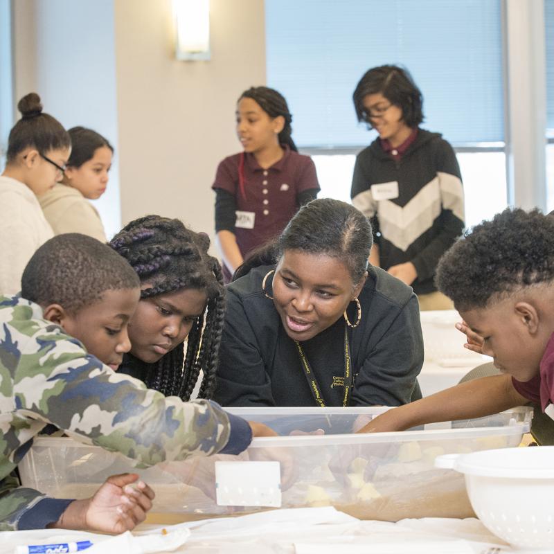 Instructor helps school age students with project.