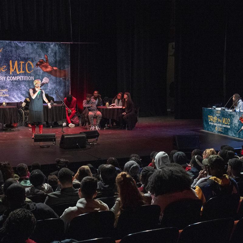 Performer onstage speaks before an audience.