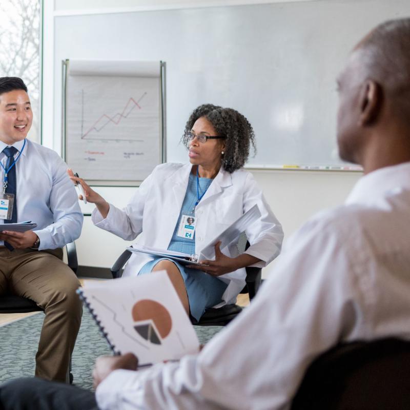 Woman in white coat speaks to a group.