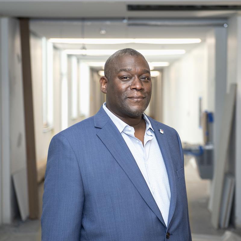 Man in business attire poses for the camera in a hallway.