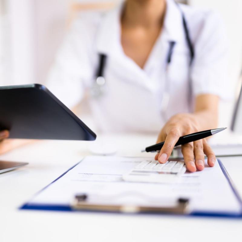 Detail of medical administrator working with forms and a tablet.