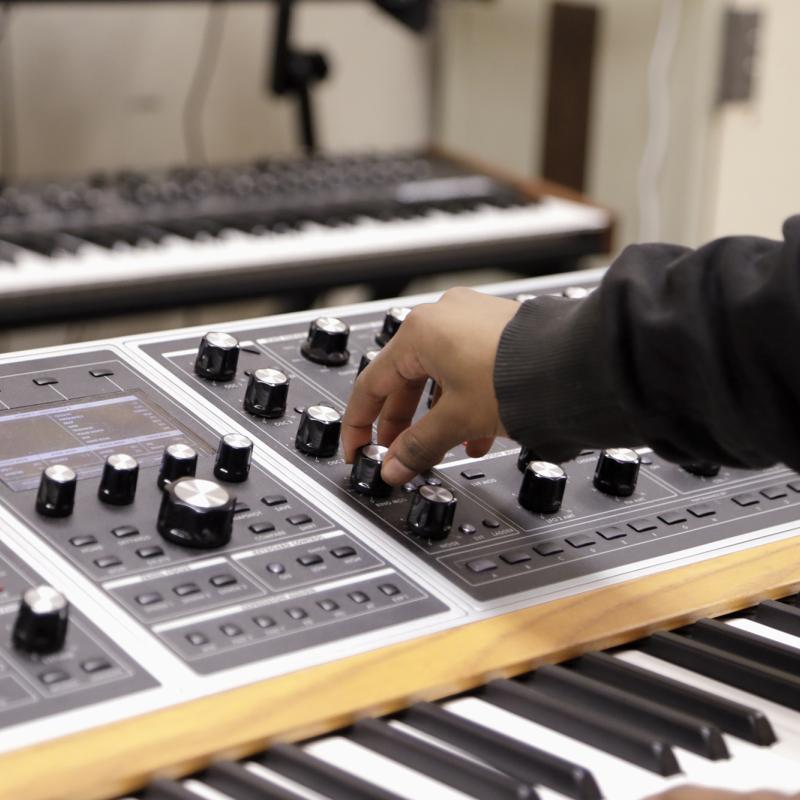 Hand adjusting a knob on a soundboard