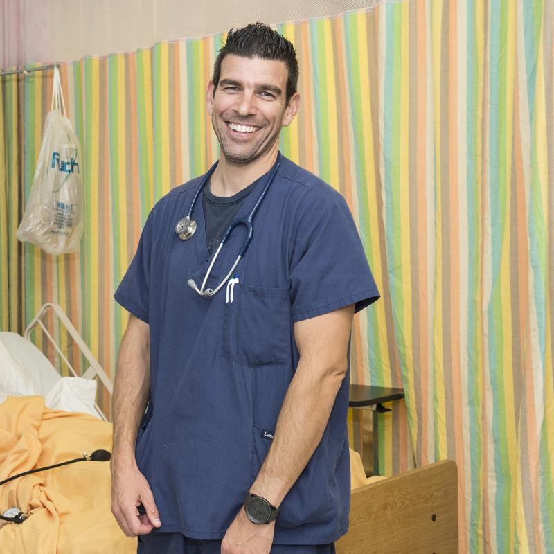 Nurse in a hospital room smiles for the camera.