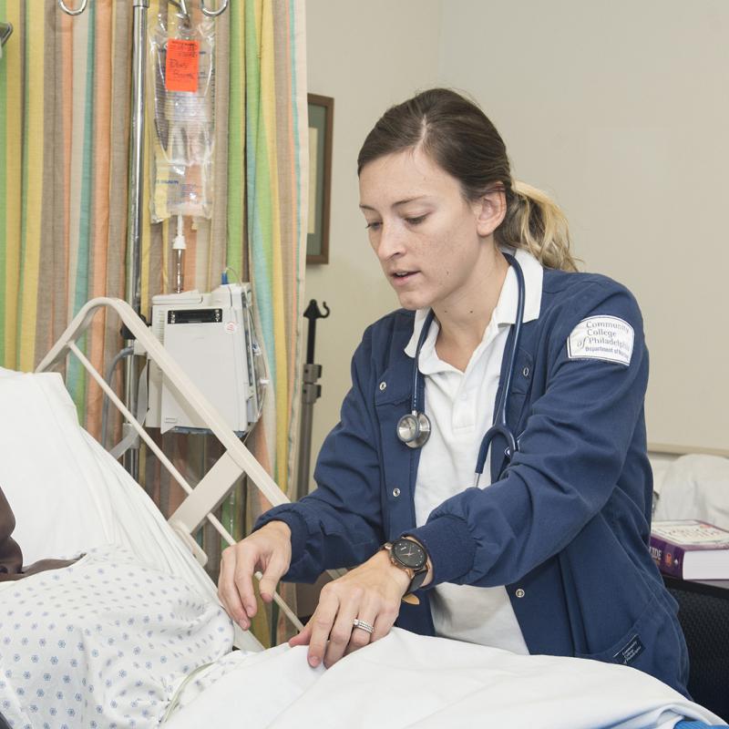 Nursing student works at a hospital bedside.