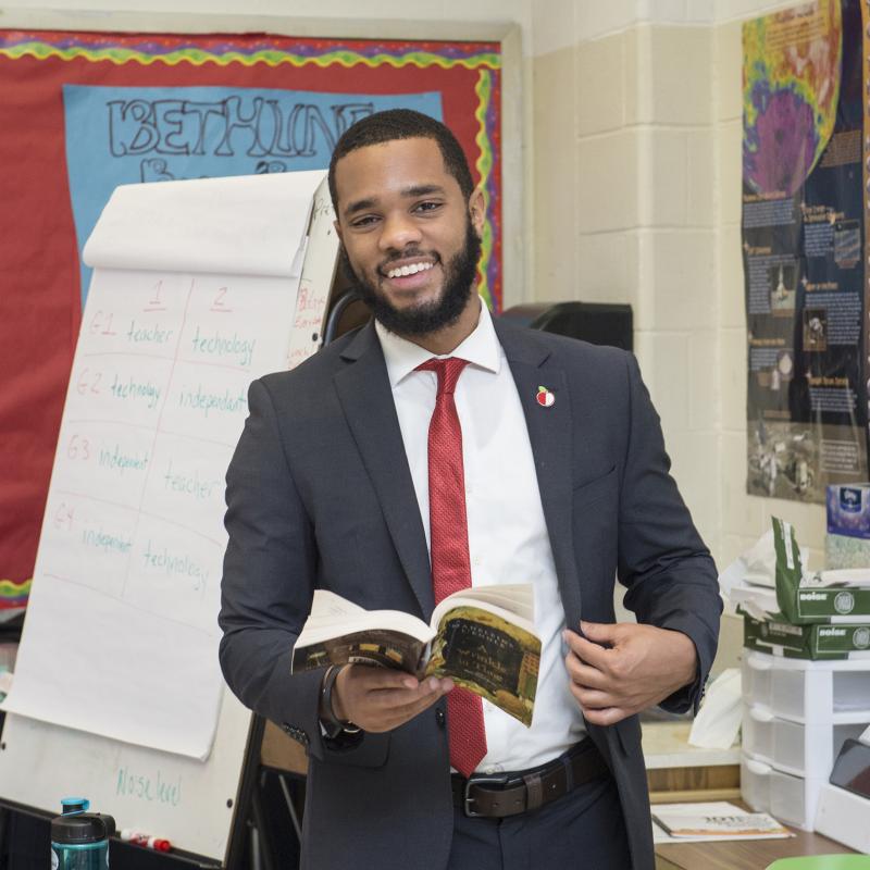 An elementary school teach in a classroom smiles for the camera.