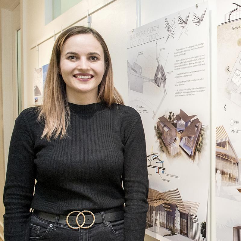 Architecture student standing proudly in front of her portfolio