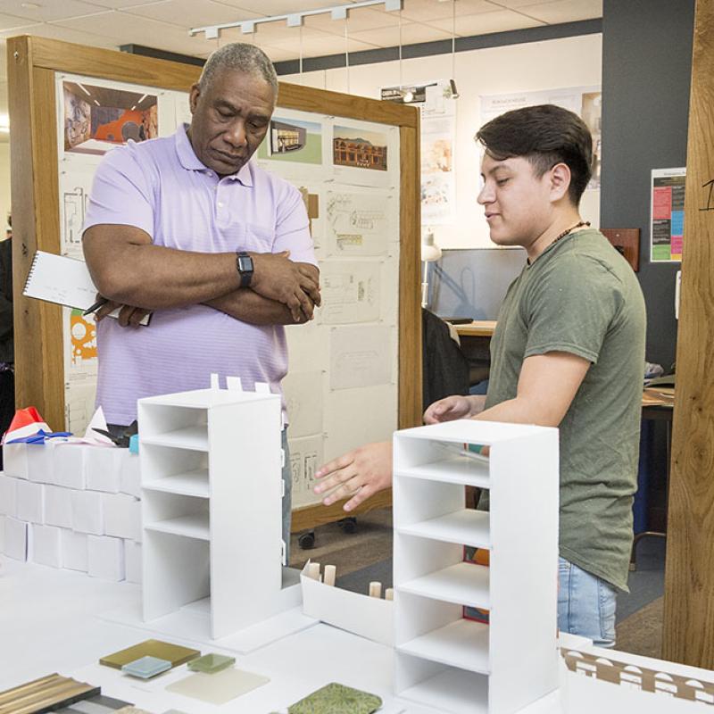 Professor listens as student presents their 3-D rendering of a building