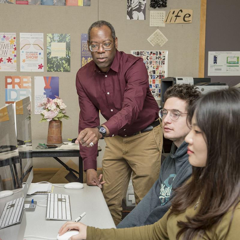 professor instructing two design students in computer lab