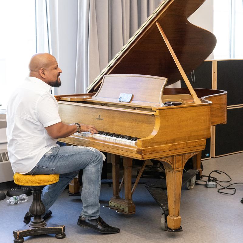 Man plays a baby grand piano.