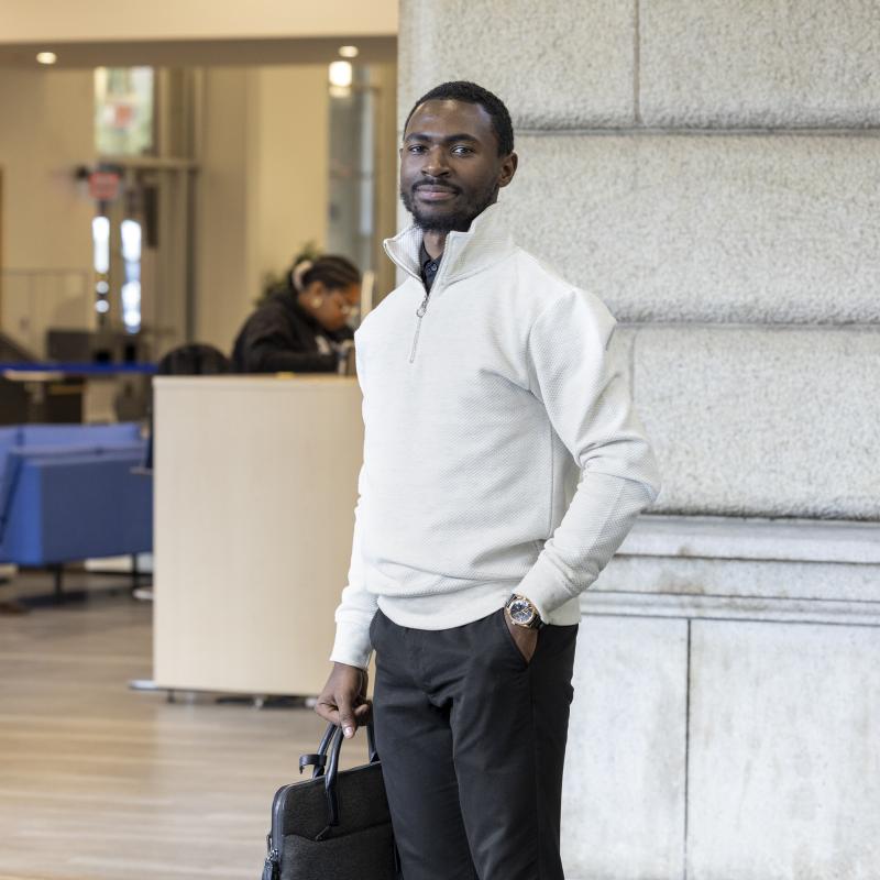 Man in business casual attire carrying briefcase poses for the camera.