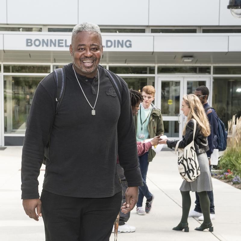 Adult student on campus smiles for the camera.