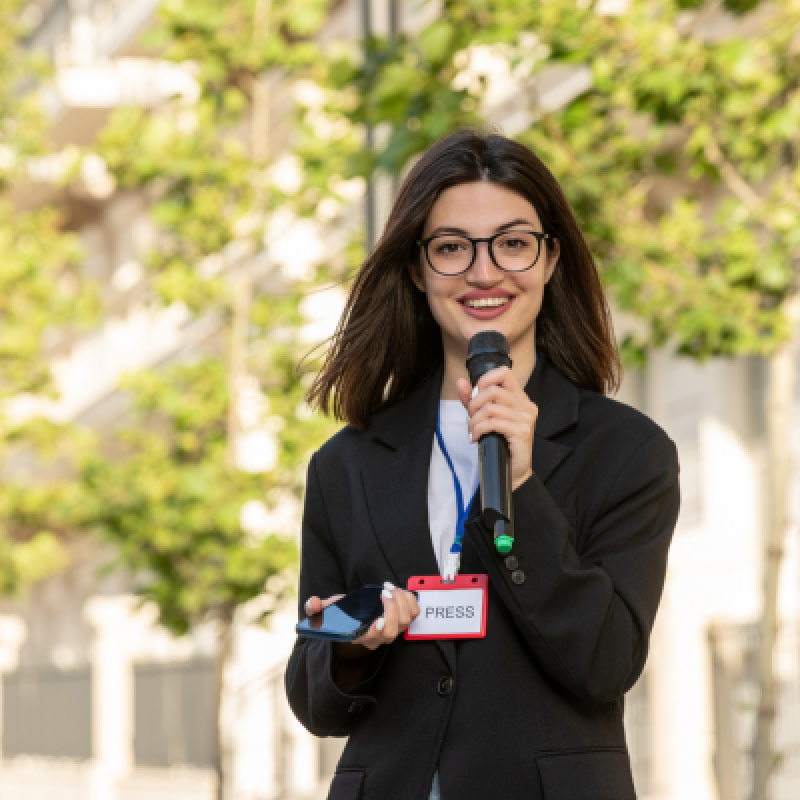Woman holding news reporter microphone and looking at a camera