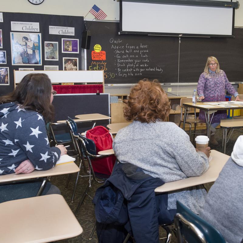 Adults sitting in a school classroom learning about early childhood education.