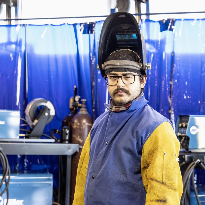Welding student wearing a welding helmet and protective gear 