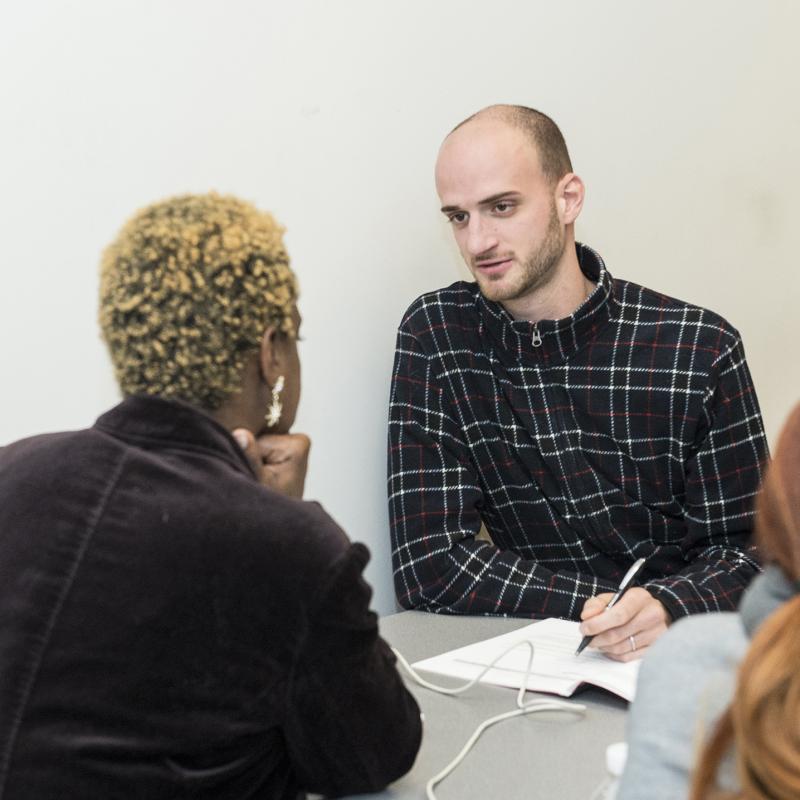 Person talking with others while writing notes