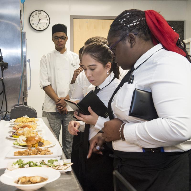 Food service manager holding a book and overseeing food production