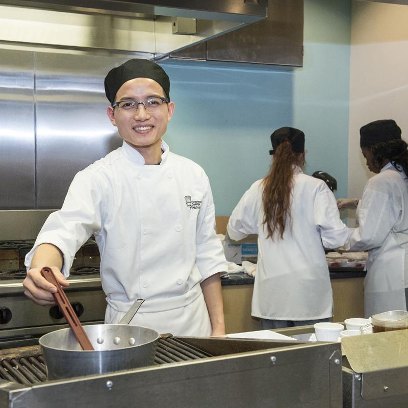 Student smiling while stirring a pot